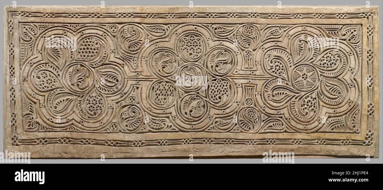 Dado Panel 10th century This carved plaster panel comes from an elaborately decorated house excavated at Nishapur, which had panels decorating the lower part of the wall (called the dado) in several rooms. The panels were originally painted in bright yellows, reds, and blues, with equally colorful murals on the plaster walls above. However, once the excavated panels were exposed to air, the bright colors quickly disappeared. It appears that to create these dado panels, a thin layer of stucco was applied to the wall and the design was sketched out using a compass and other drawing tools. Then t Stock Photo