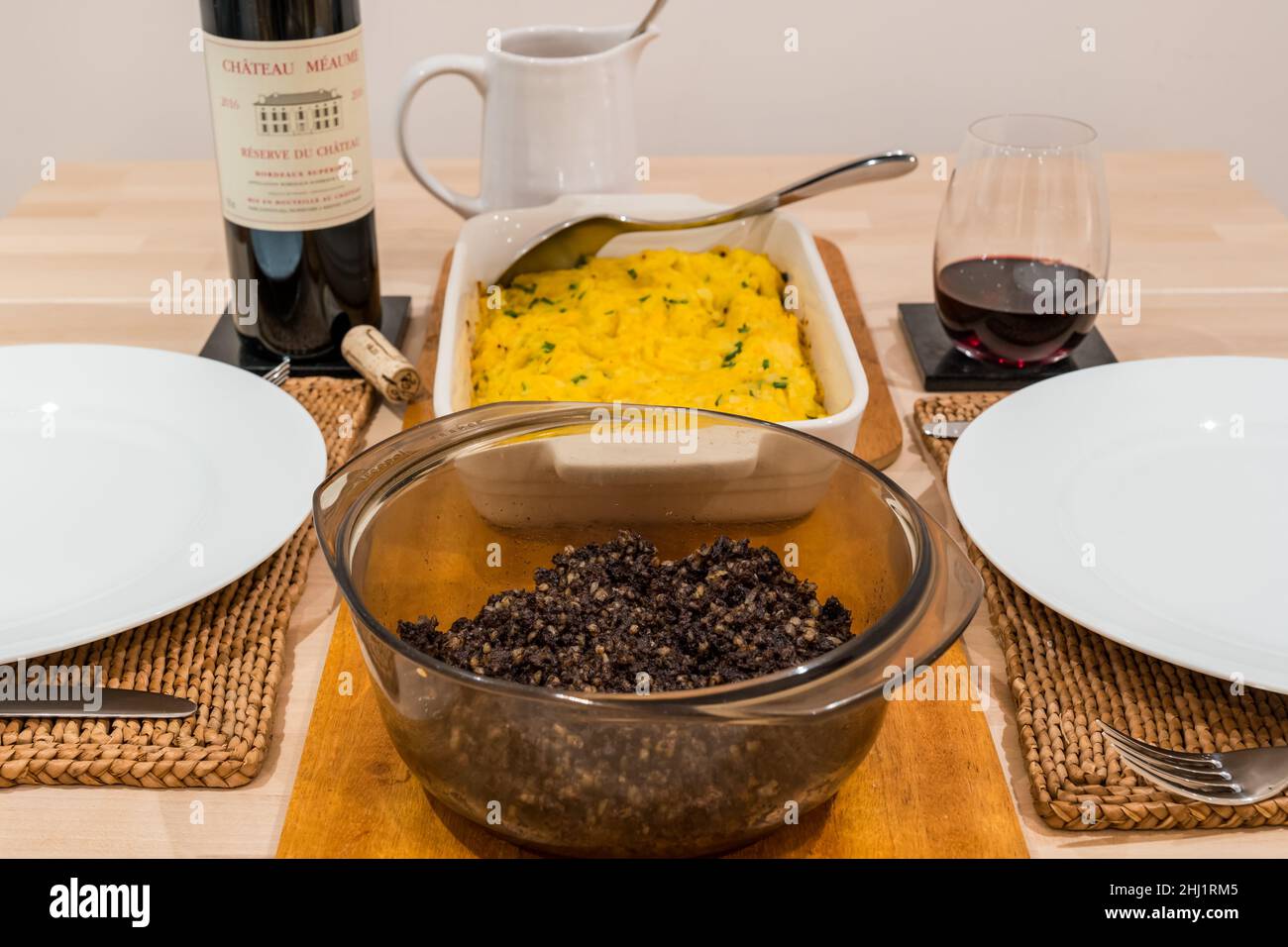 Traditional Scottish Burns Night supper meal: haggis & clapshot (mashed potato & turnip or swede) & bottle of Bordeaux claret Chateau Meaume red wine Stock Photo