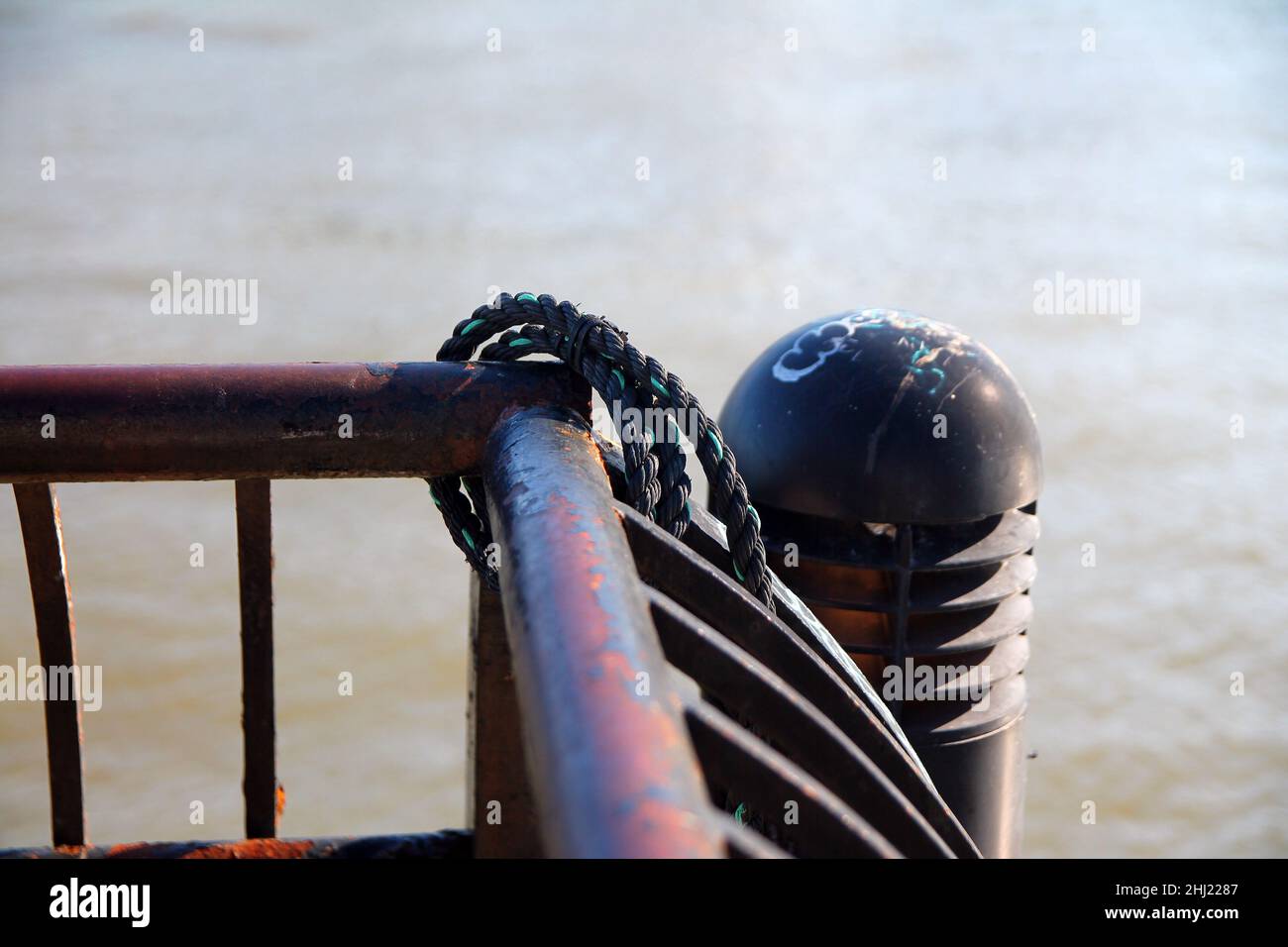 An old marine rope around a rust fence of a harbor, used to sail in the ...