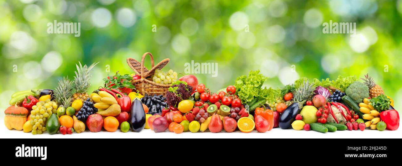 Panoramic collection bright fresh fruits and vegetables on blurred green background. Stock Photo