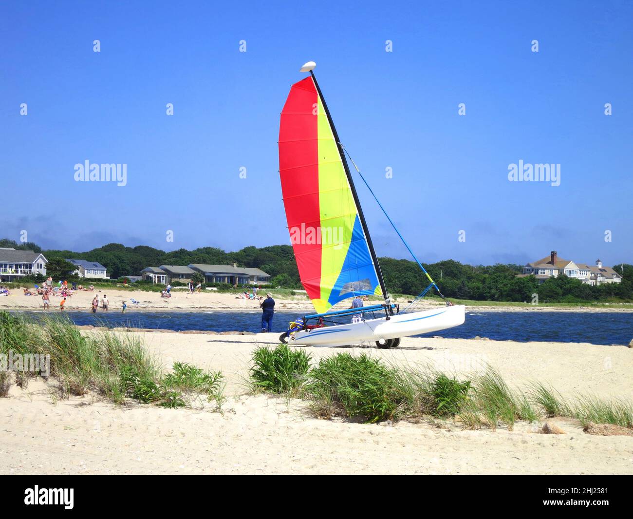 Sailboat with Red,Yellow and Blue sails and blue water and blue sky on a sandy beach off Lewis Bay near Hyannis Harbor,in Cape Cod, Massachusetts,USA. Stock Photo