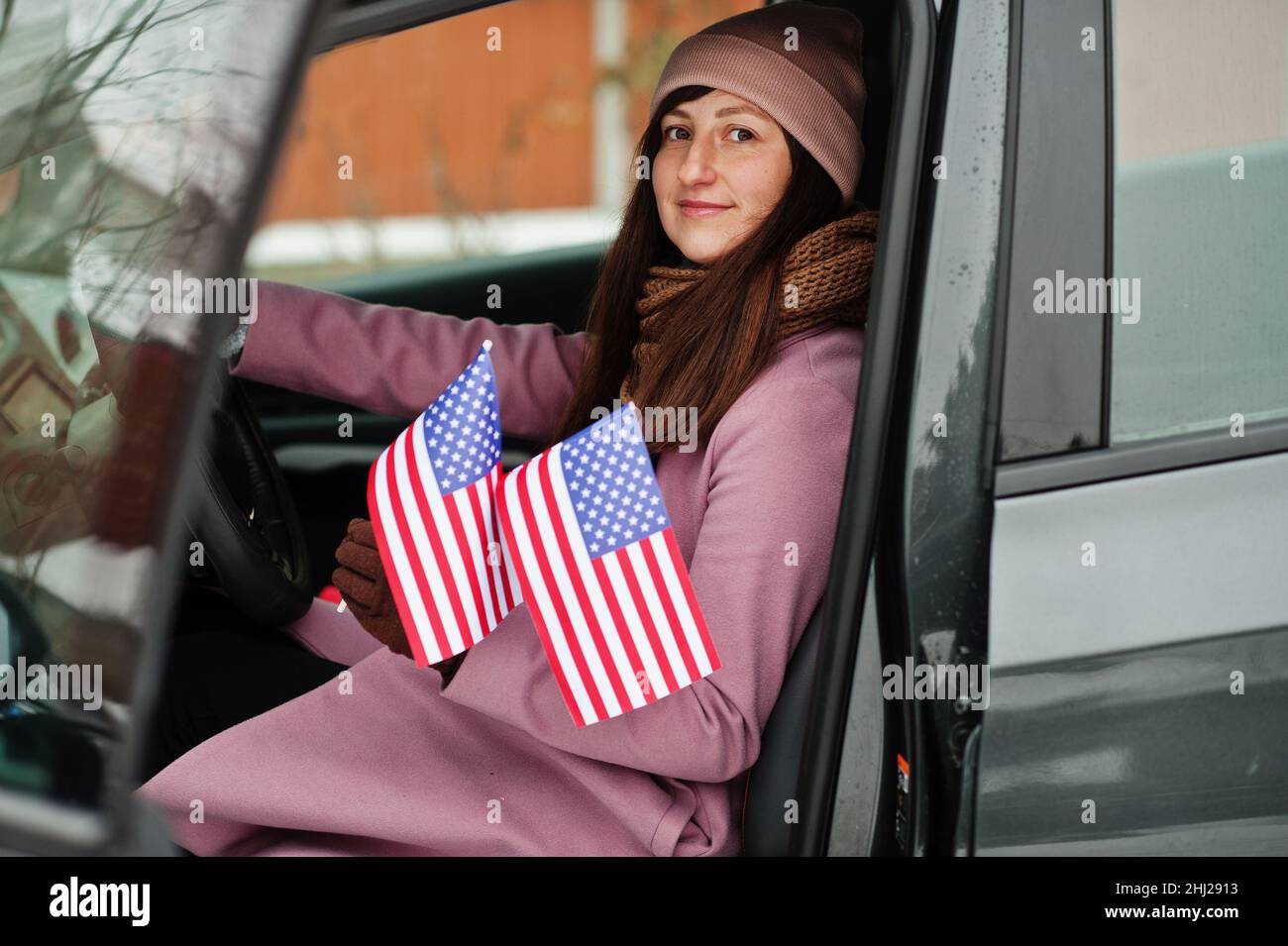 Young woman with USA flag siting on car. Stock Photo