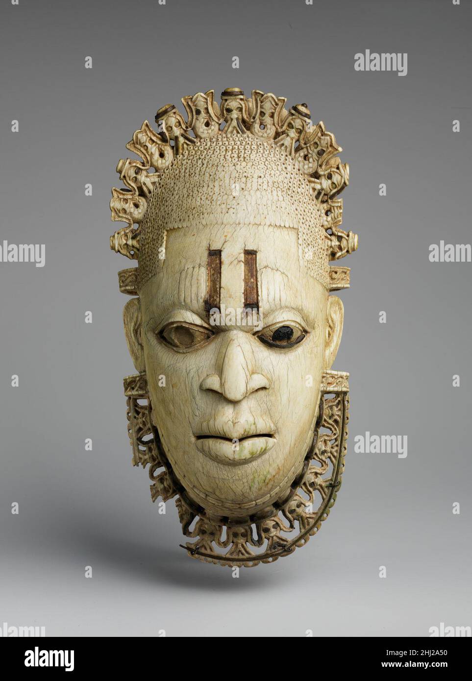 Queen Mother Pendant Mask: Iyoba 16th century Edo peoples This ivory pendant mask is one of a pair of nearly identical works; its counterpart is in the British Museum in London. Although images of women are rare in Benin's courtly tradition, these two works have come to symbolize the legacy of a dynasty that continues to the present day. The pendant mask is believed to have been produced in the early sixteenth century for the King or ObaEsigie, the king of Benin, to honor his mother, Idia. The oba may have worn it at rites commemorating his mother, although today such pendants are worn at annu Stock Photo