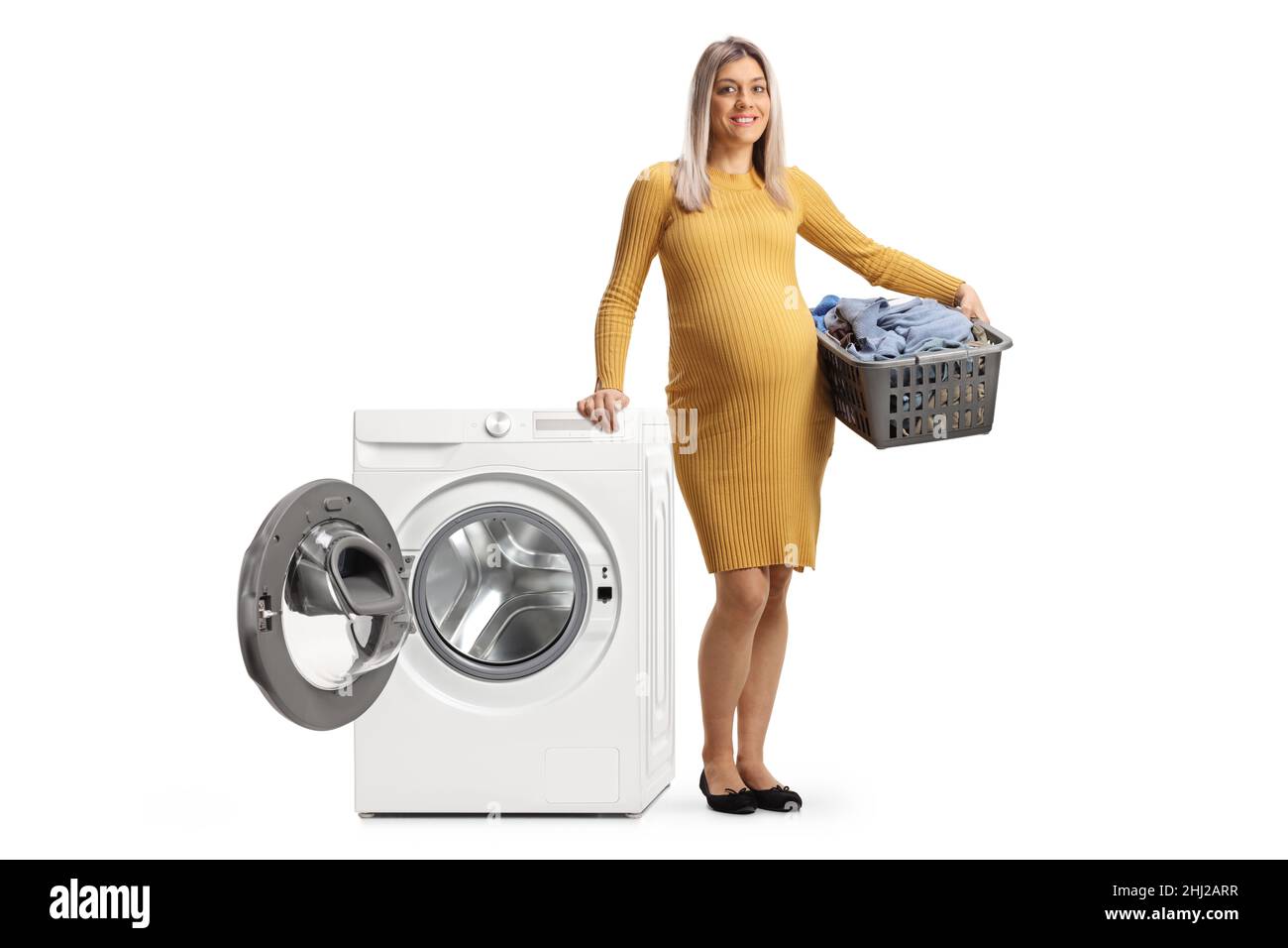 Pregnant woman with a laundry basket leaning on a washing machine
