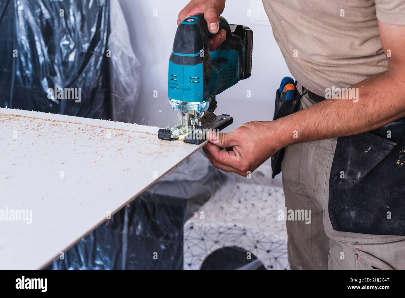 Worker cutting a wood board with a jigsaw. Home renovations Stock Photo