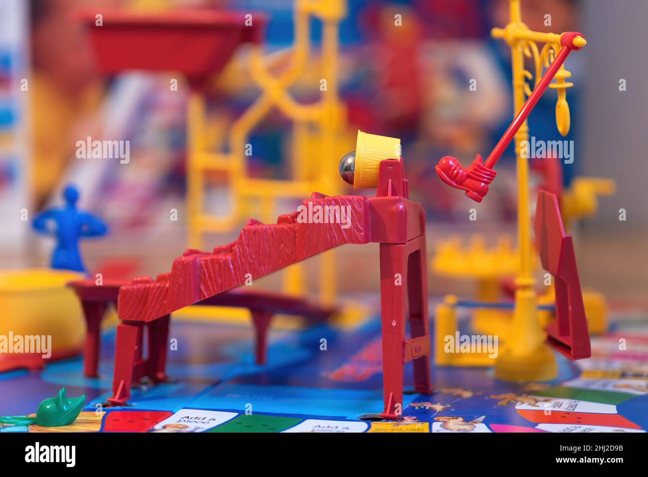 A close up view of the red boot kicking the yellow bucket over and tipping out the steel ball in the Mouse Trap board Game. Stock Photo