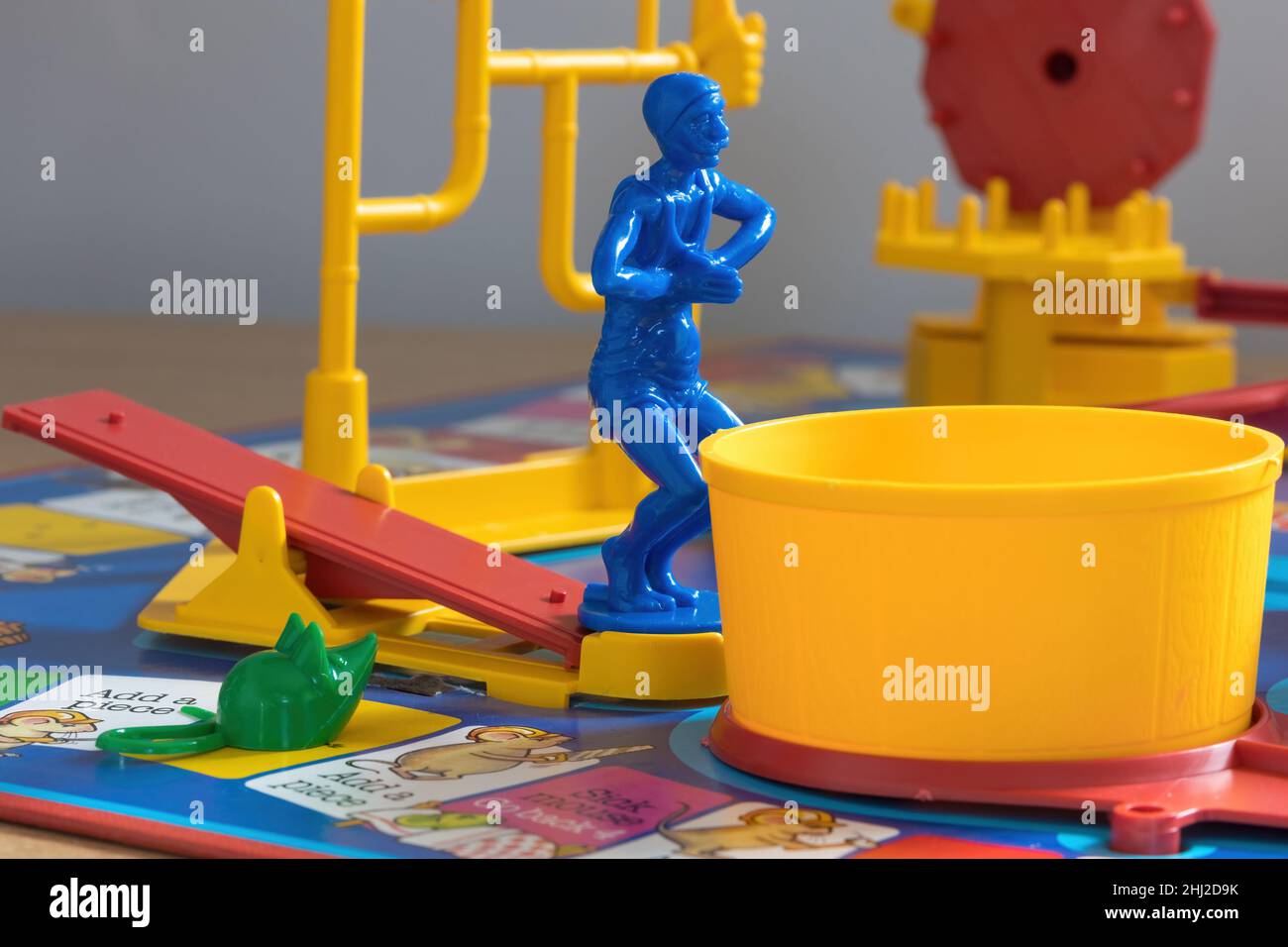 A close up shot of the blue diver standing on the See-Saw and a green mouse on the board. The diver is waiting to dive into the yellow tub. Stock Photo