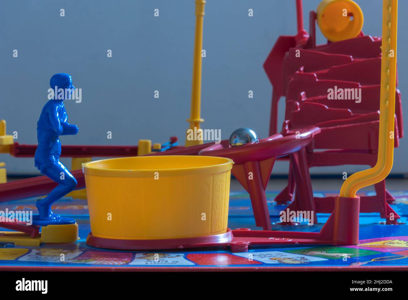 The blue diver on MouseTrap board game waits for the steel ball as it rolls down the ramp before diving into the yellow Tub that releases the cage Stock Photo