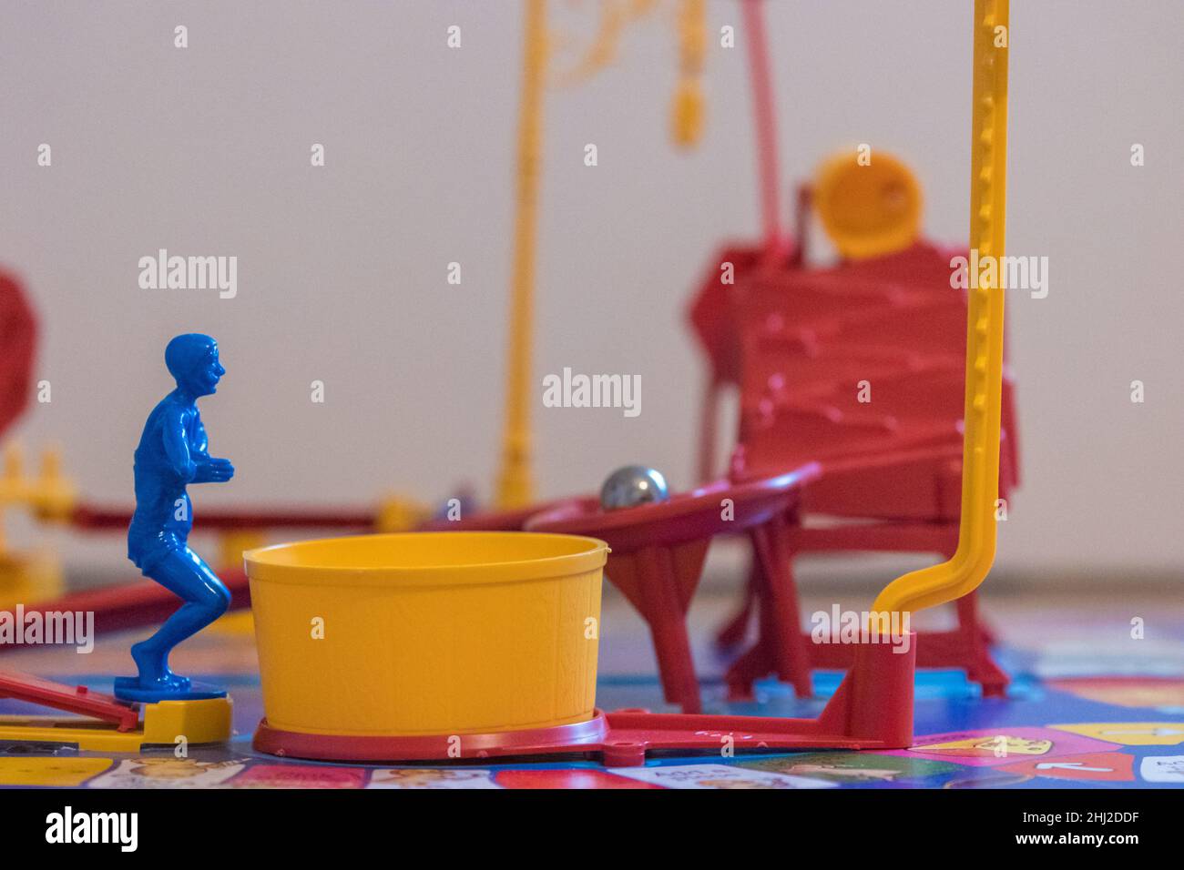 The blue diver on Mouse Trap board game waits for the steel ball as it rolls down the ramp before diving into the yellow Tub that releases the cage Stock Photo