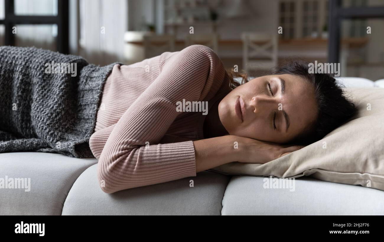 Young serene Latin woman sleep on sofa at home Stock Photo