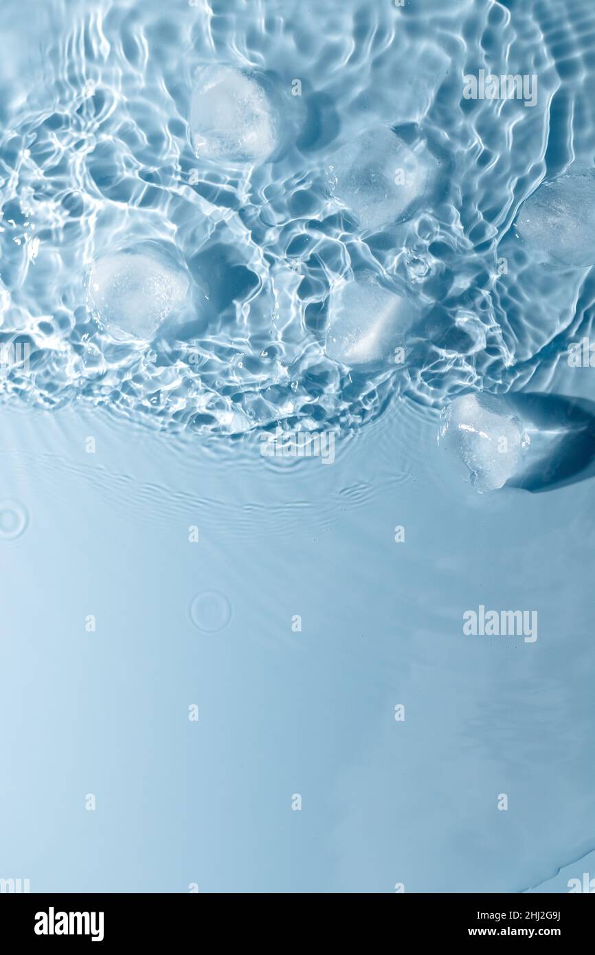 Ice cubes with water drops scattered on a blue background, top view ...