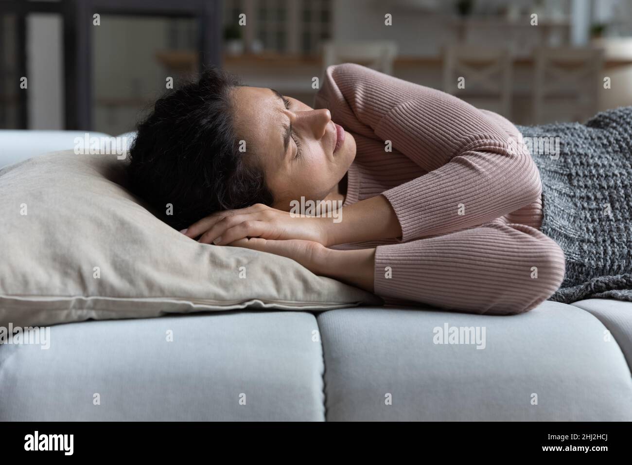 Woman frowning lying on sofa suffer from daytime restless sleep Stock Photo