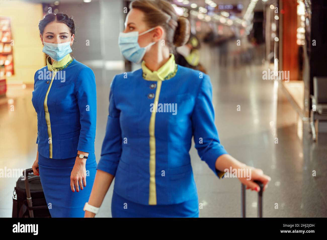 Flight attendants in medical masks carrying travel bags at airport