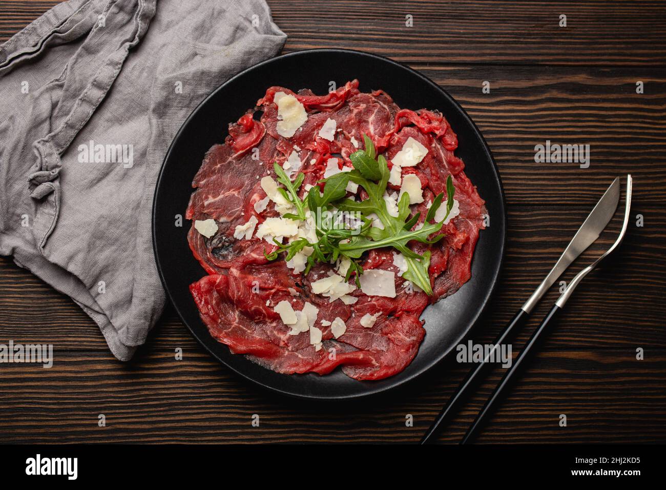Cold meat appetizer Beef carpaccio with parmesan cheese and arugula on