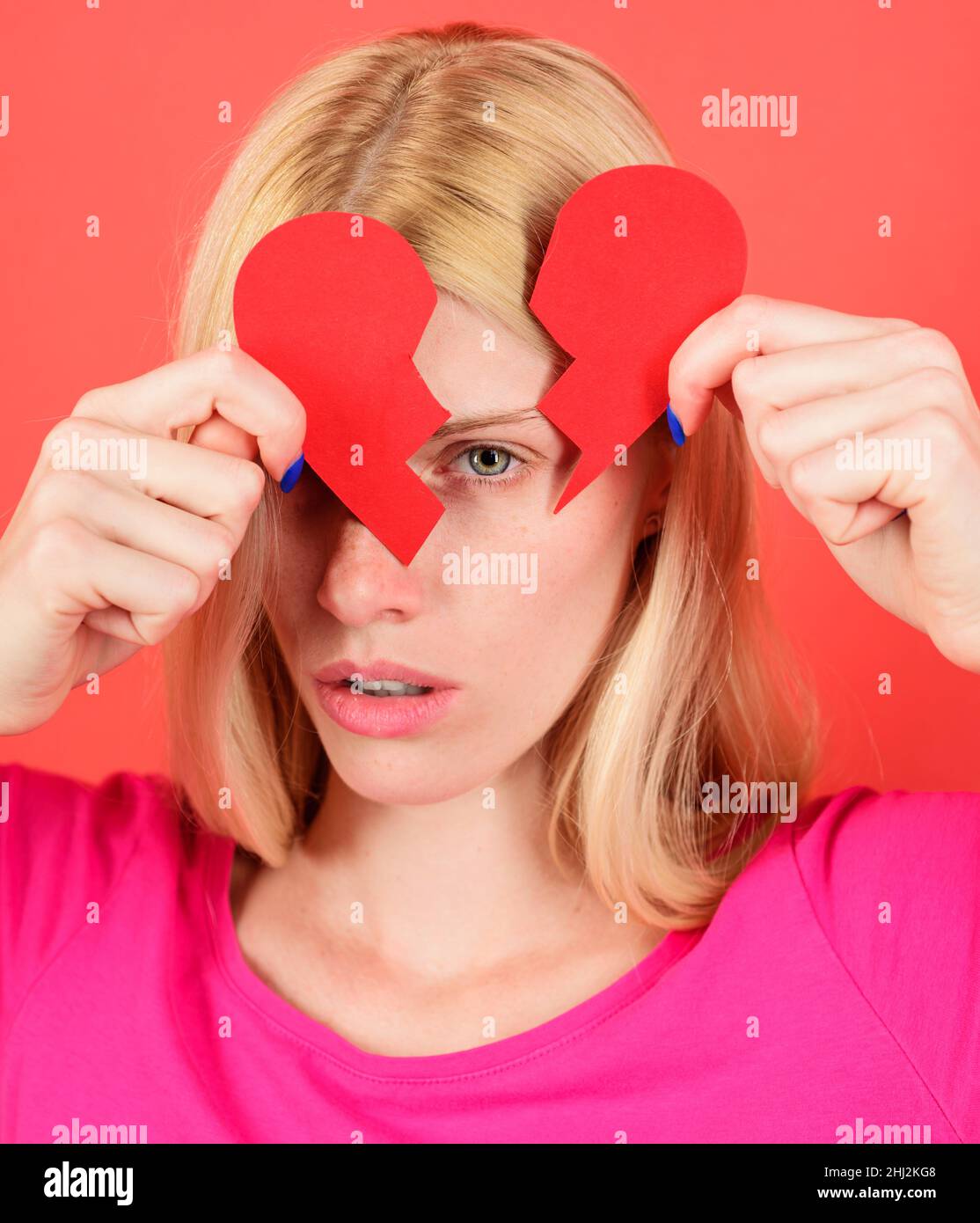 Sad woman with cut paper heart. Girl with heartbreak. Valentines day. Broken heart. Unhappy love. Stock Photo