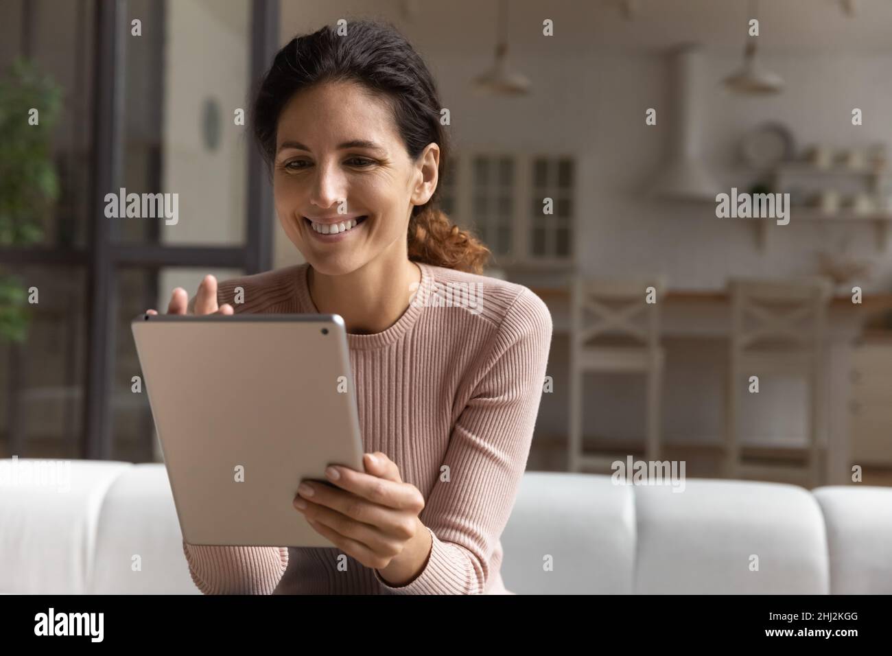 Happy woman sit on sofa at home with digital tablet Stock Photo