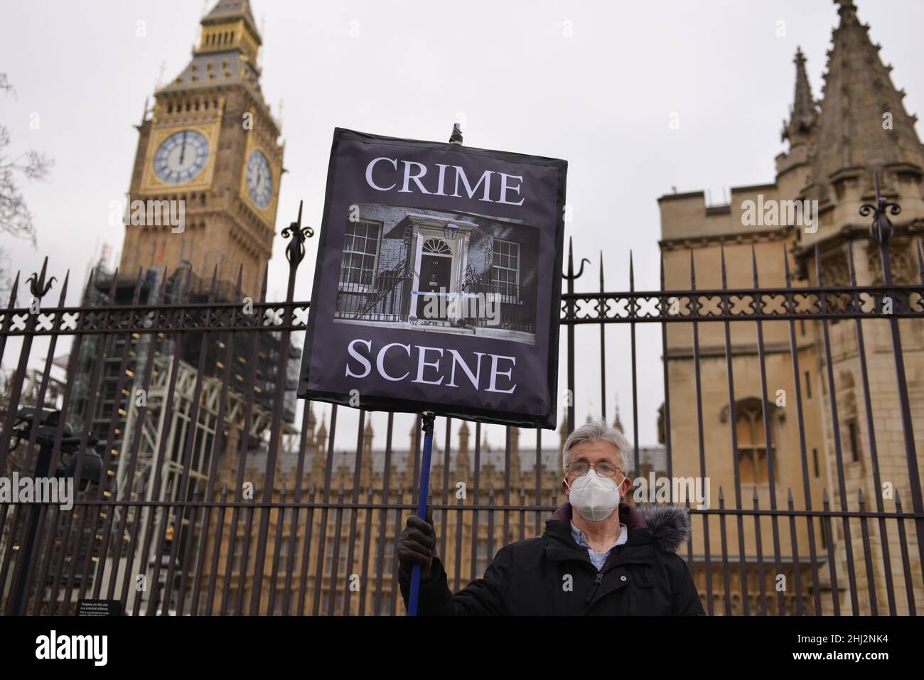 Protesters stand outside the parliament with a placard depicting 10 Downing Street as a 'crime scene' and an anti-Boris Johnson placard, during the demonstration. Demonstrators gathered opposite UK Parliament as Boris Johnson faced Prime Minister's Questions (PMQs) amid the 'Partygate' scandal Stock Photo