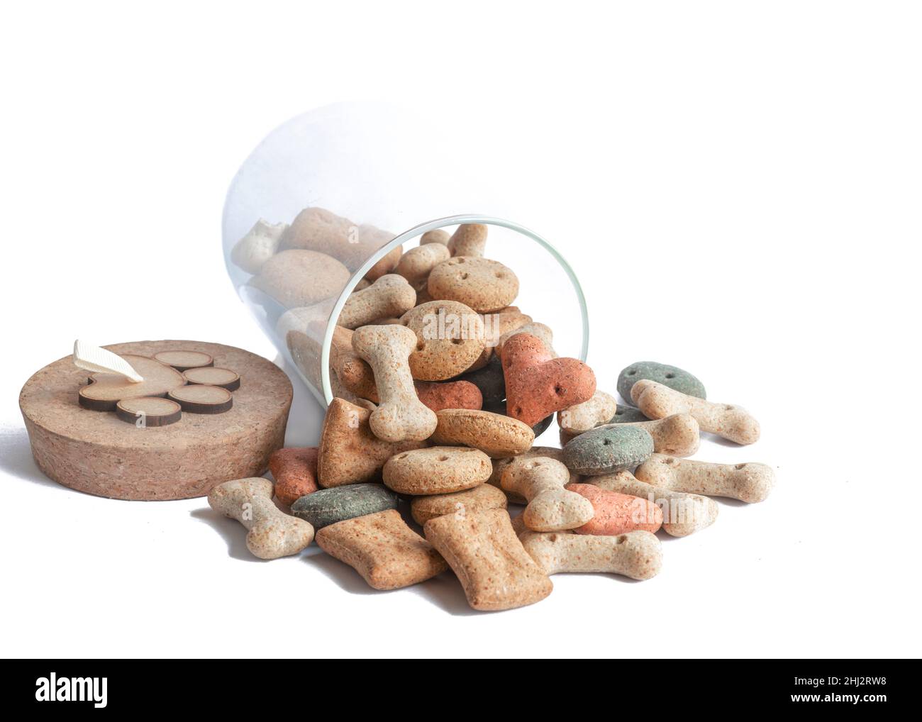 Different coloured and shaped dog treats or biscuit in a glass jar with lid shot on a white background Stock Photo
