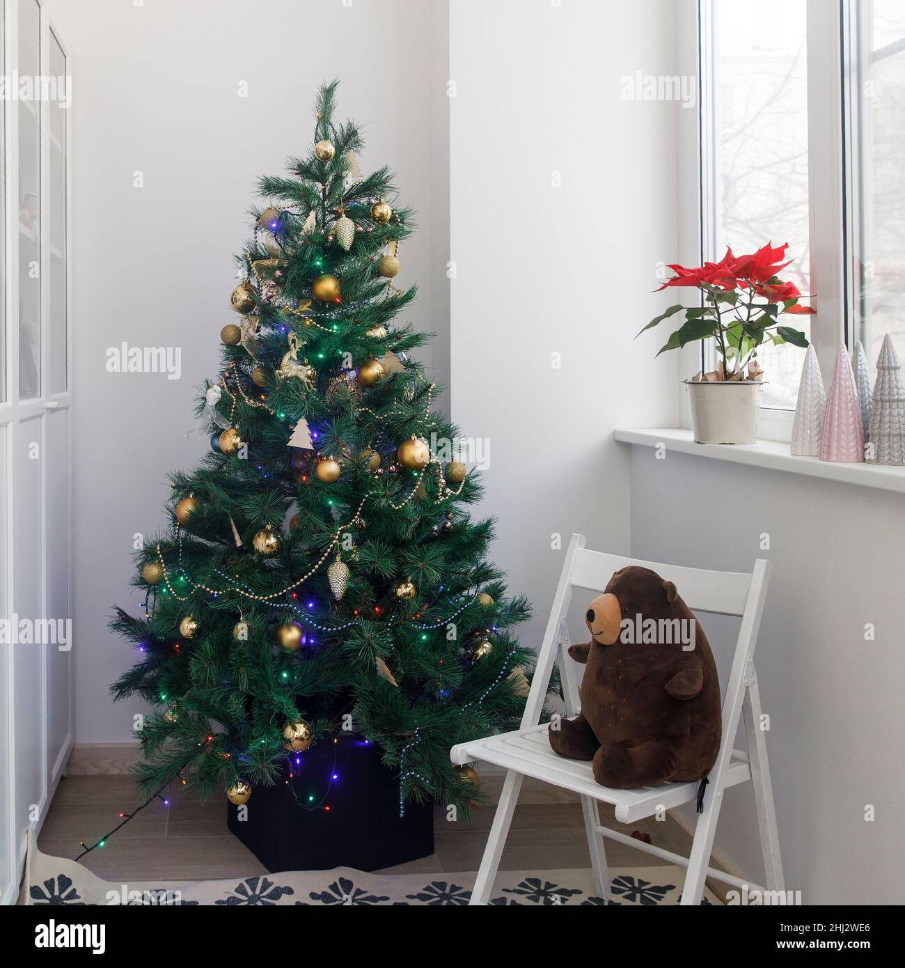 A decorated Christmas tree with a garland and wooden toys stands in the ...