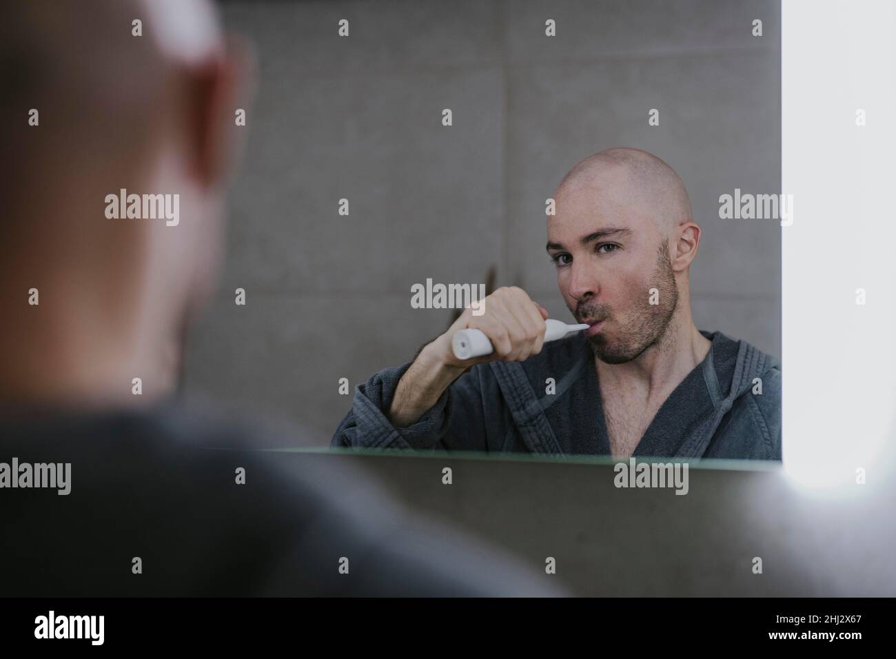 Man brushing his teeth in front of the bathroom mirror Stock Photo