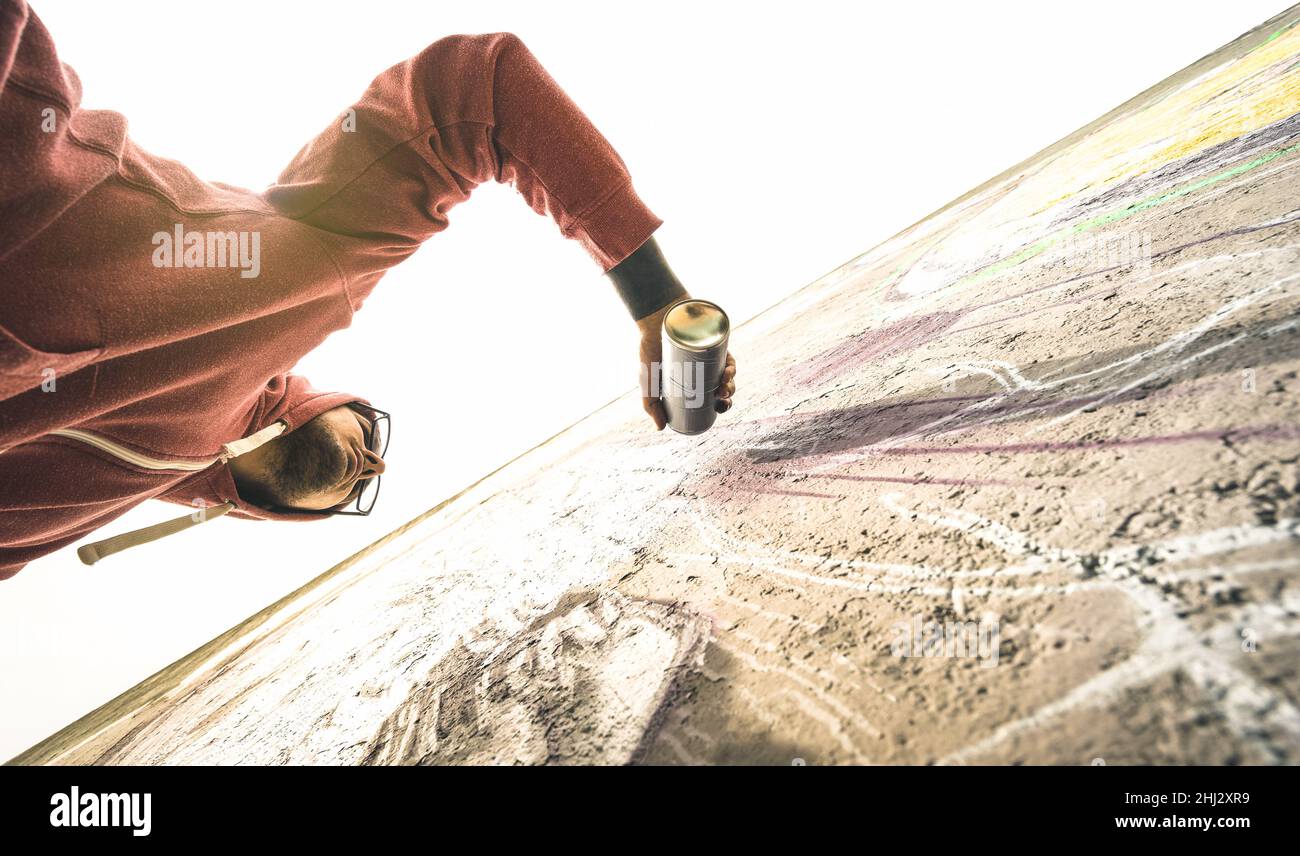Lower view of street artist painting graffiti on generic wall - Modern ...