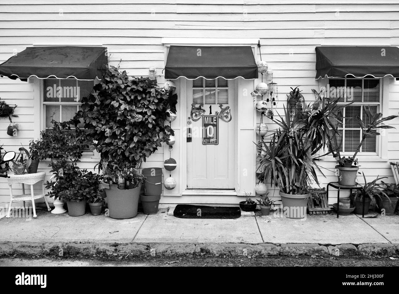 Front door with Mile Marker “0” and decorative geckos in Key West, Florida, FL, USA.  Hanging fishing buoys and a red awning surround the door. Stock Photo