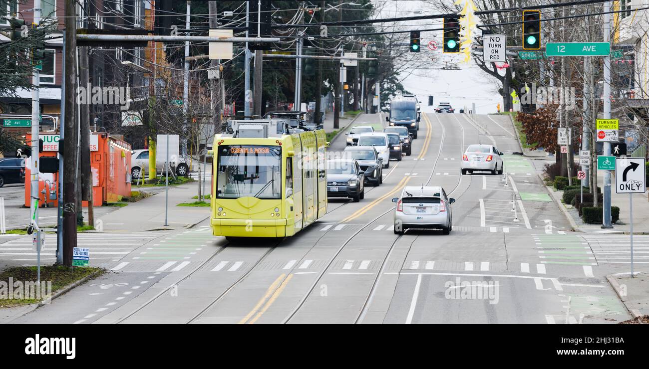 Seattle - January 23, 2022; Street scene in Seattle as a yellow streetcar stores energy while moving downhill through regenerative breaking Stock Photo