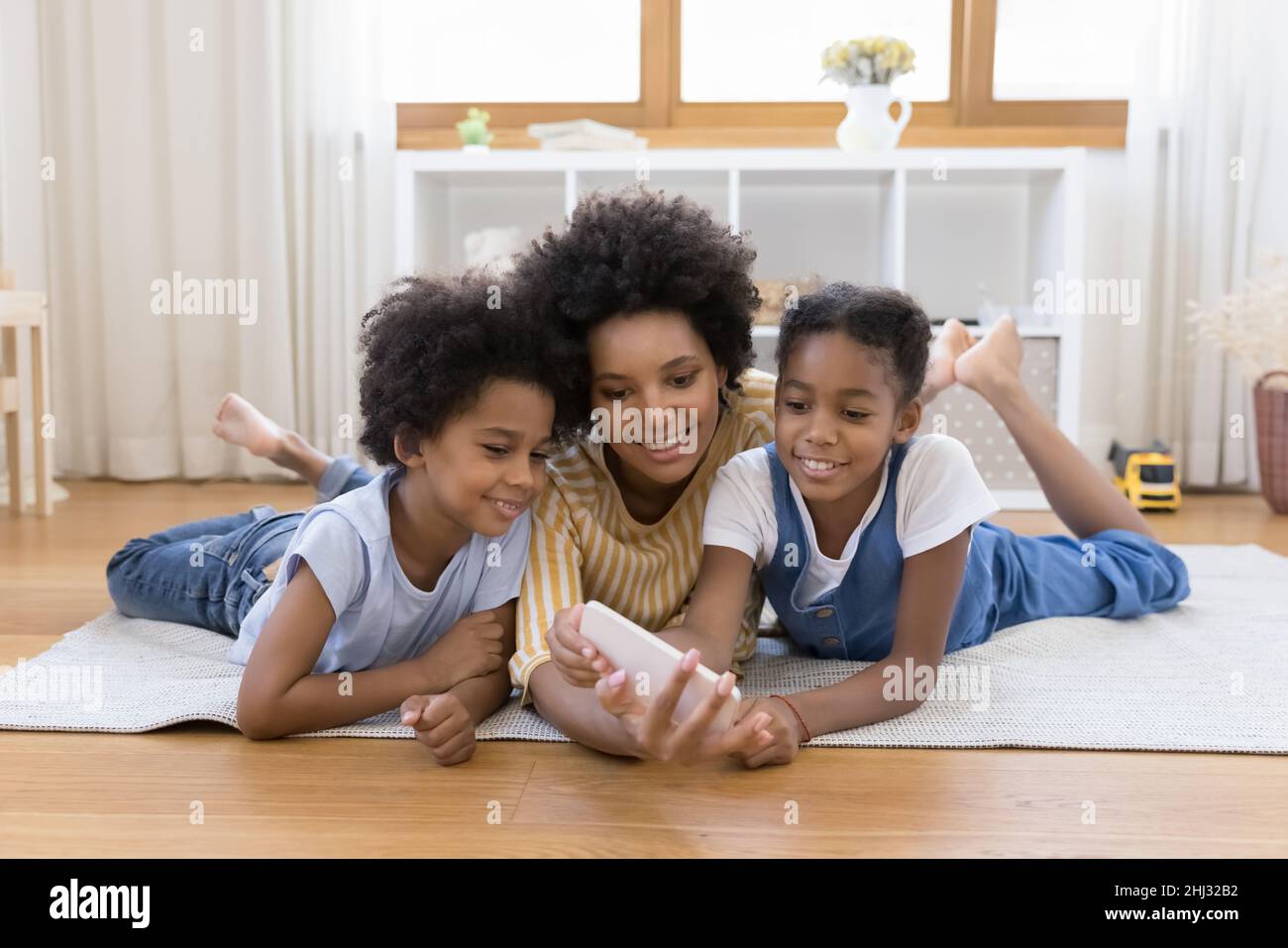 African woman her children having fun using cellphone at home Stock Photo