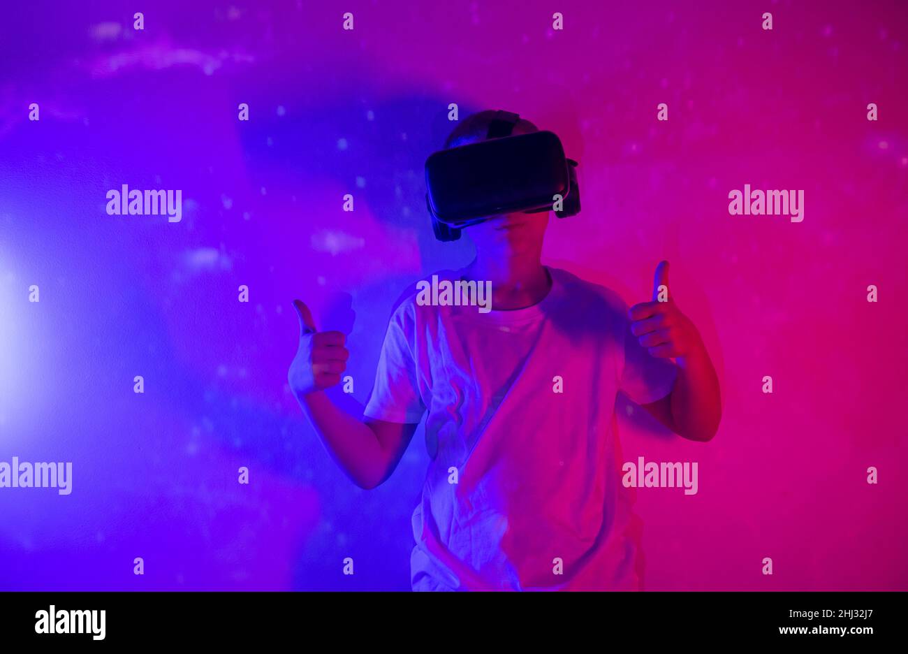 Young boy playing VR goggle on neon lighting. People, technology and cyberspace concept Stock Photo
