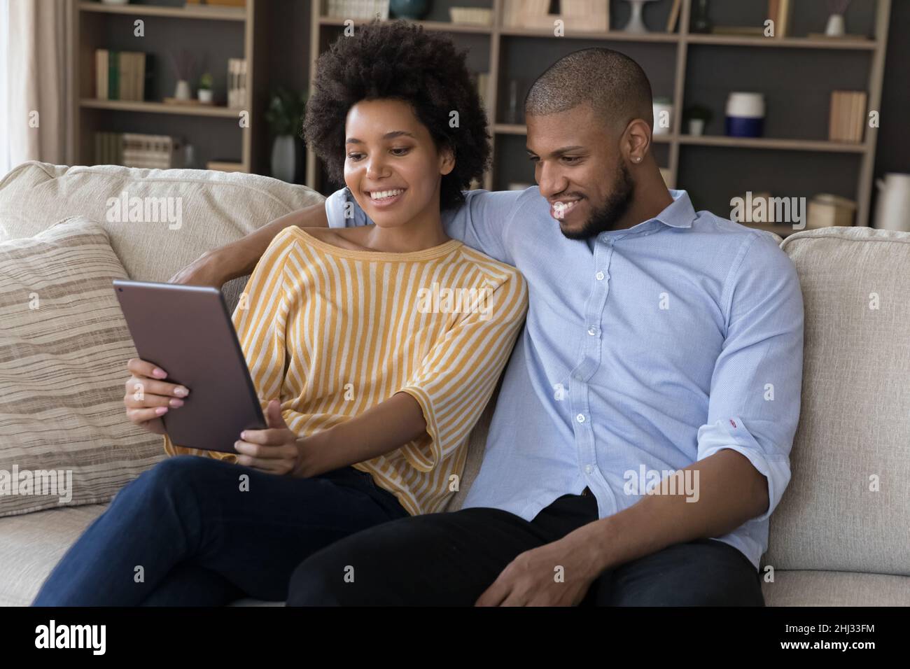 Beautiful African couple relaxing on sofa using digital tablet Stock Photo