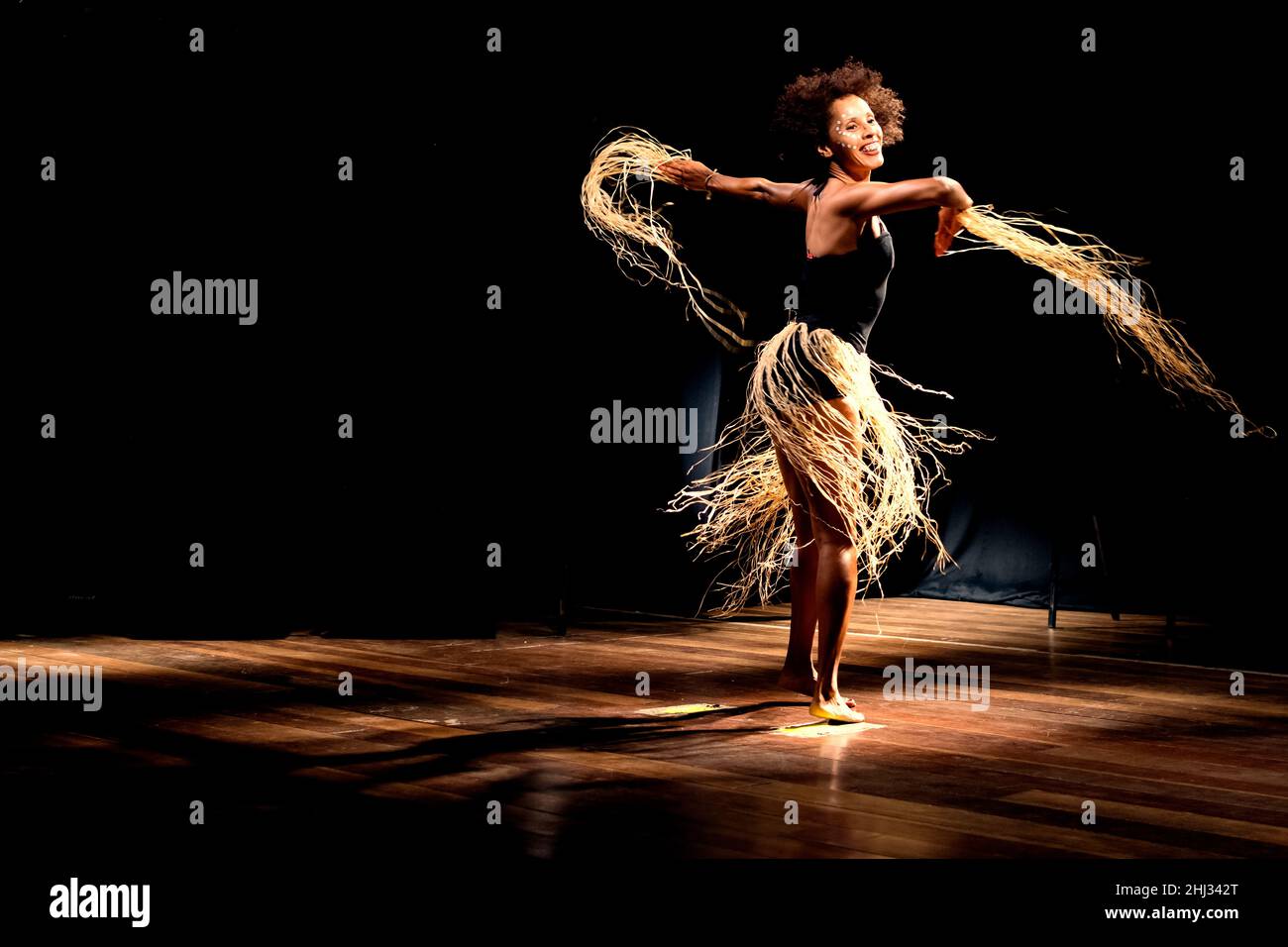 Contemporary dancer dancing in theater with black background and straw accessory. Salvador Bahia Brazil. Stock Photo