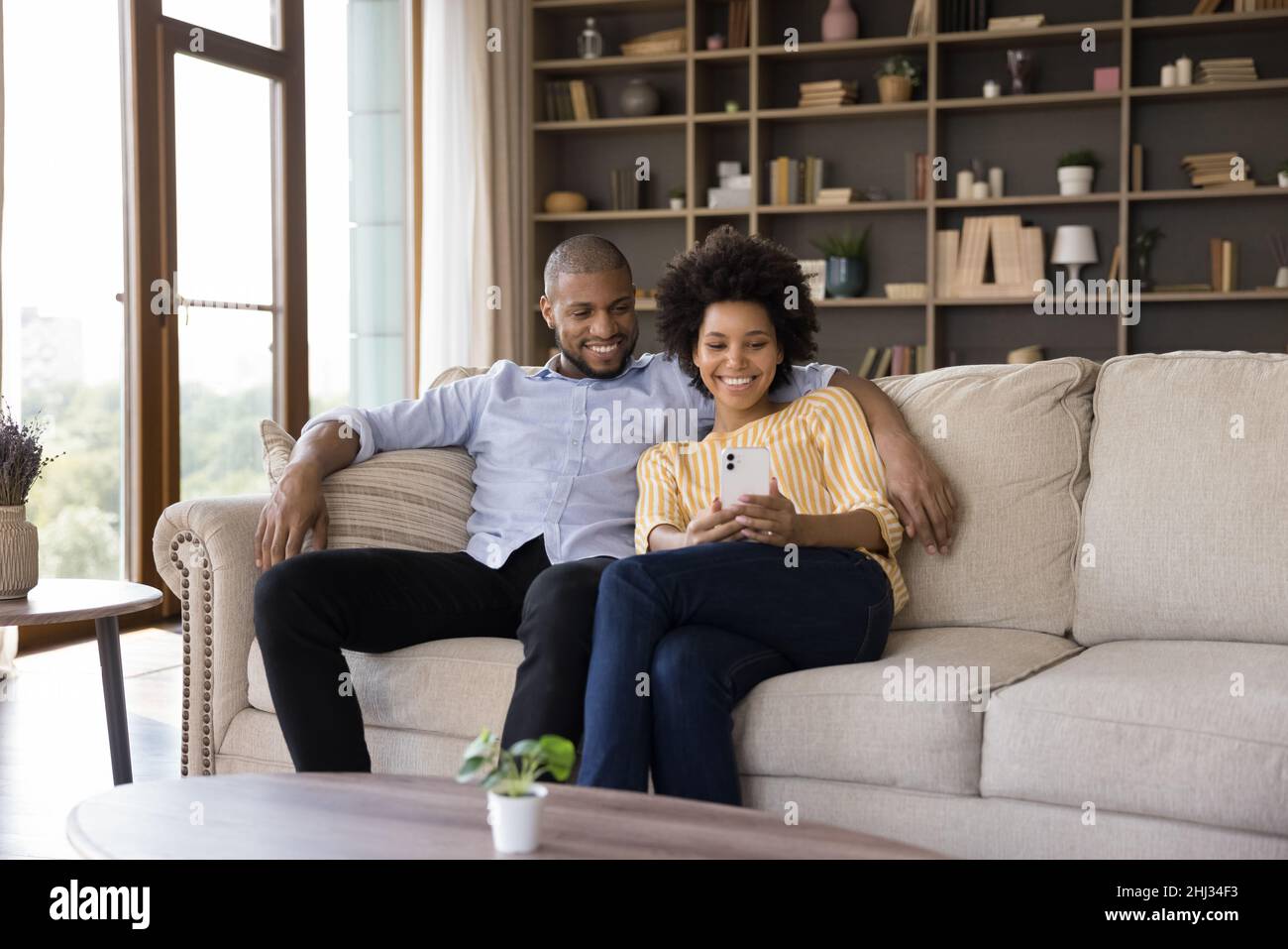 Happy African couple sit on sofa with cell phone Stock Photo - Alamy