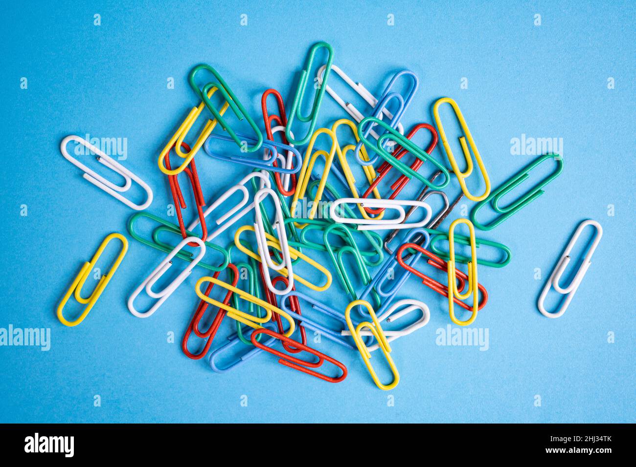 some colored paper clips on a blue surface Stock Photo