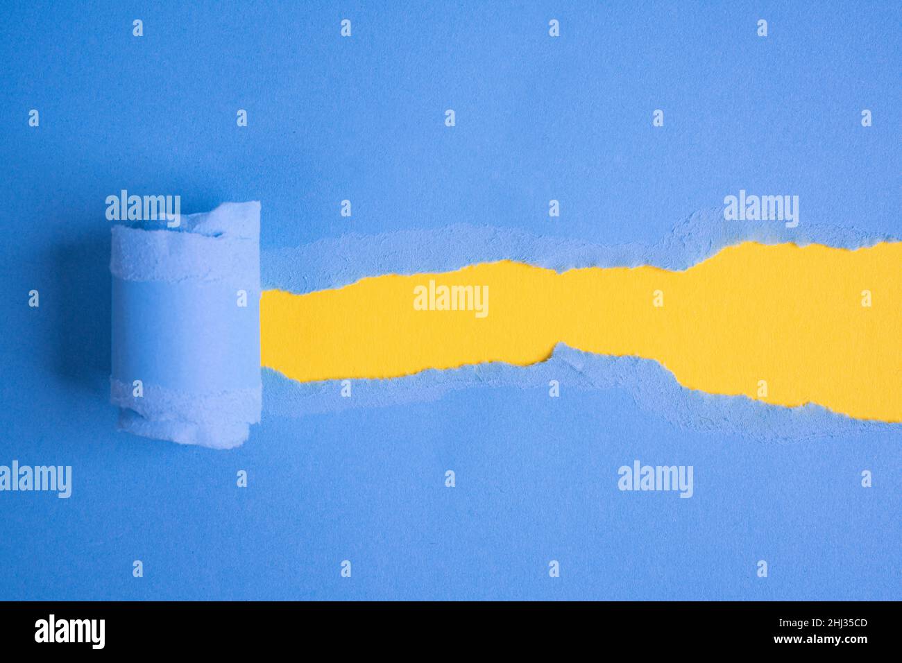a torn blue sheet of paper that opens a window on a yellow background Stock Photo