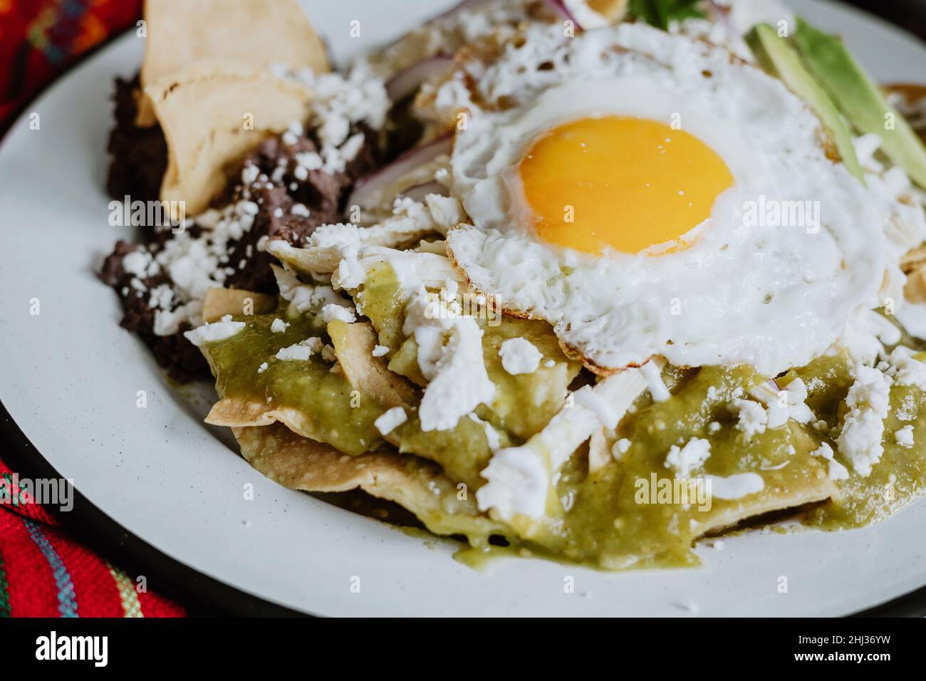 mexican green chilaquiles with fried egg, chicken and spicy green sauce traditional breakfast in