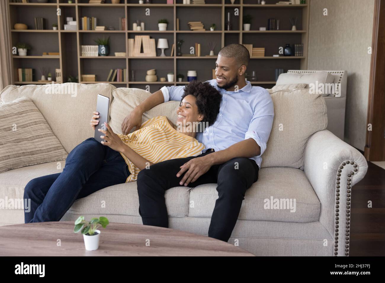 African spouses relaxing on couch in living room using tablet Stock Photo