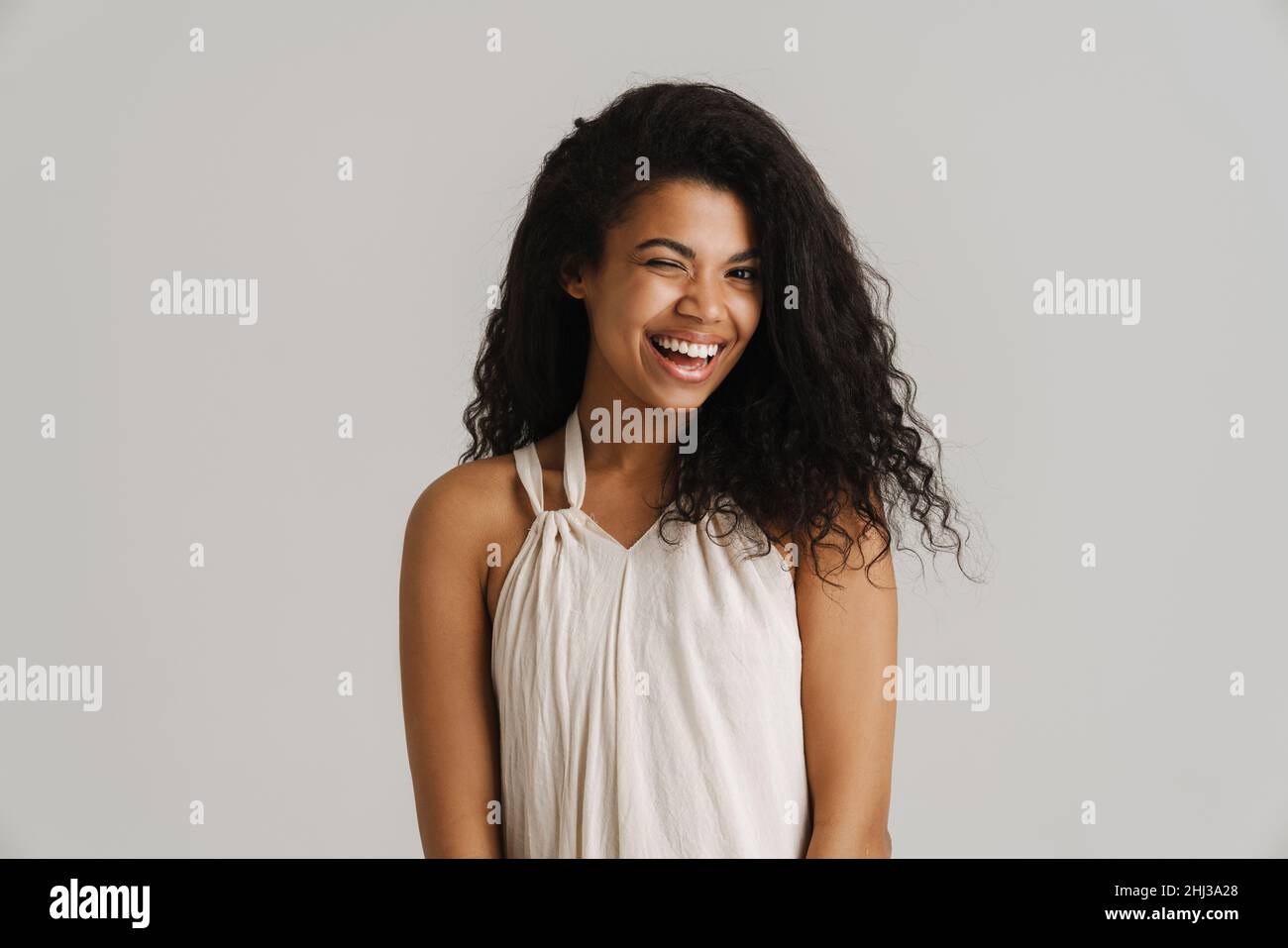 Black young woman in dress smiling and wink at camera isolated over ...