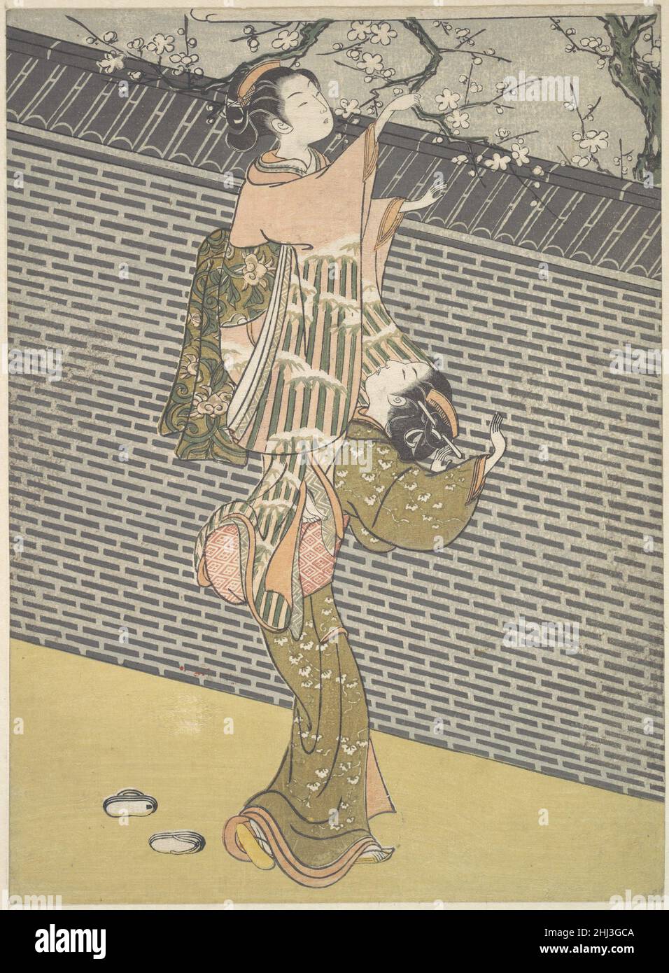 Plucking a Branch from a Neighbor's Plum Tree ca. 1768 Suzuki Harunobu Japanese This print is an excellent example of Harunobu's artistic taste—reflecting nonsensuous tenderness and exquisiteness of figures. Casting off her sandals, a young woman has climbed onto her maid's back to break off a branch of a plum tree growing over a tall wall with a tiled ridge. The two women are elegant and gentle despite their tomboyish behavior. The rigid and monotonous pattern of bricks in the fence is a foil for the graceful figures. Despite Harunobu's depiction of these two young women as innocent, the expr Stock Photo