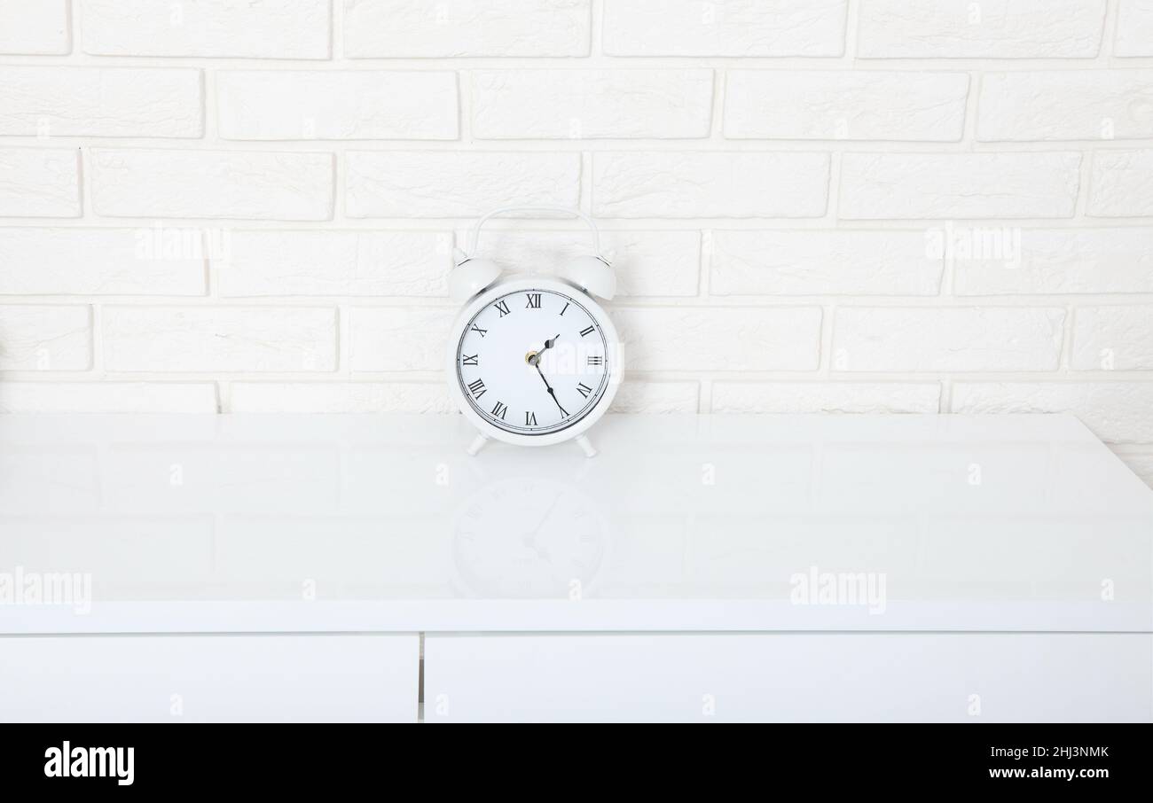 Retro alarm clock with twenty five minutes after one o'clock near brick