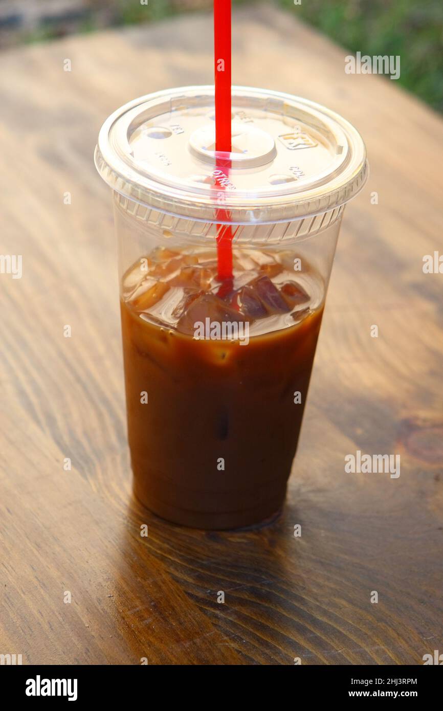 Half a cup of iced coffee outside on a park bench, representative of the morning, and good morning at that Stock Photo