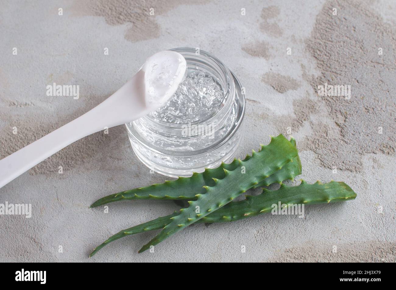 Gel with hyaluronic acid and aloe vera branches in a glass jar on a concrete background Stock Photo