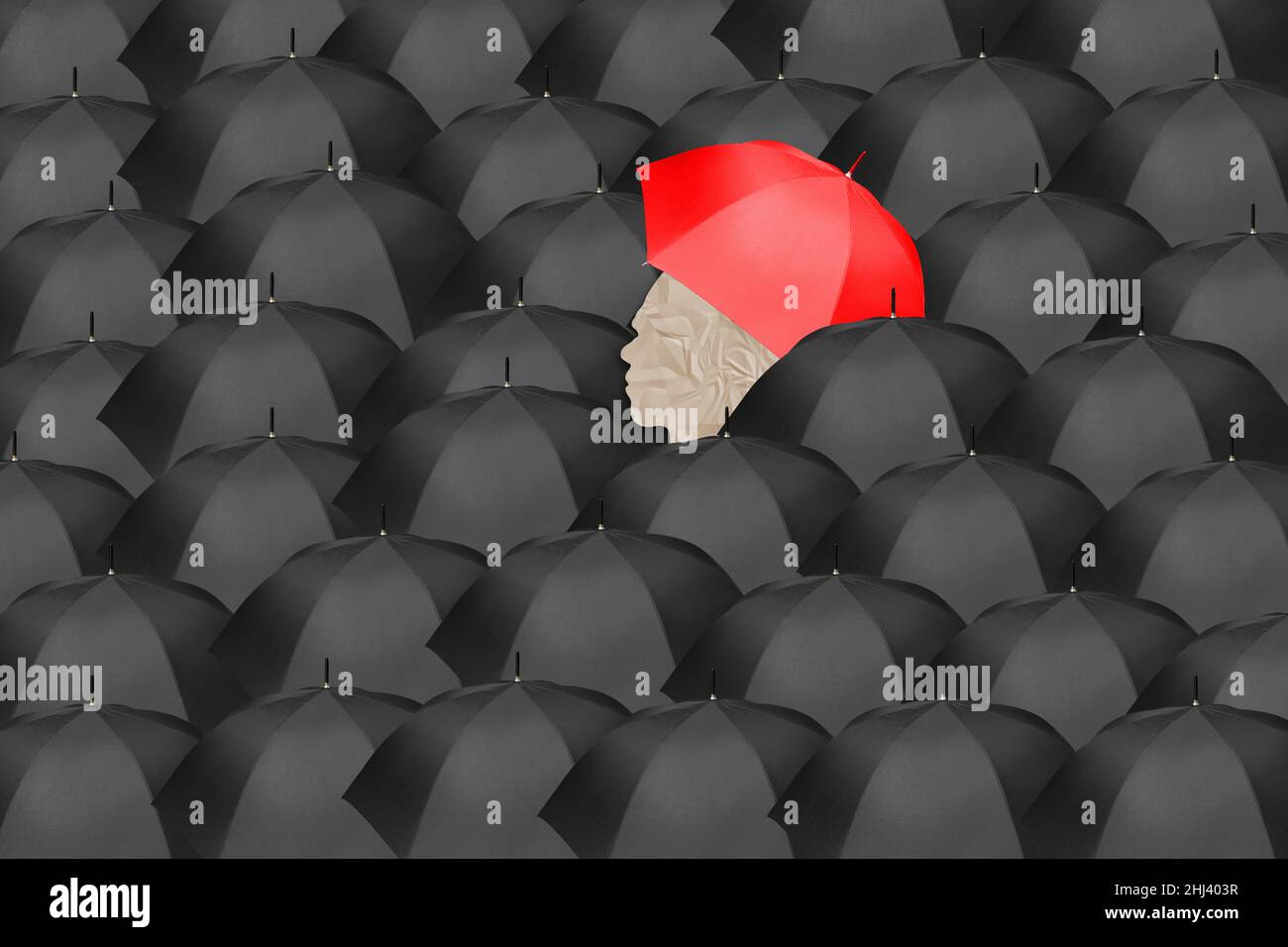 Sea of black umbrellas with one person holding a red umbrella in the center, symbolizing leadership, innovation, individuality, audacity, uniqueness. Stock Photo