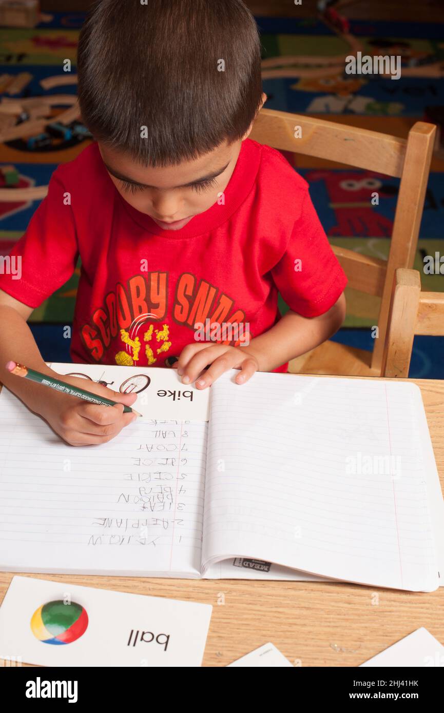 Education Preschool Boy At Table Writing Words That Begin With The Letter B In His Notebook 