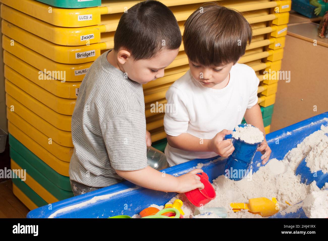 Education Preschool 4-5 year olds two boys playing together at sand table Stock Photo