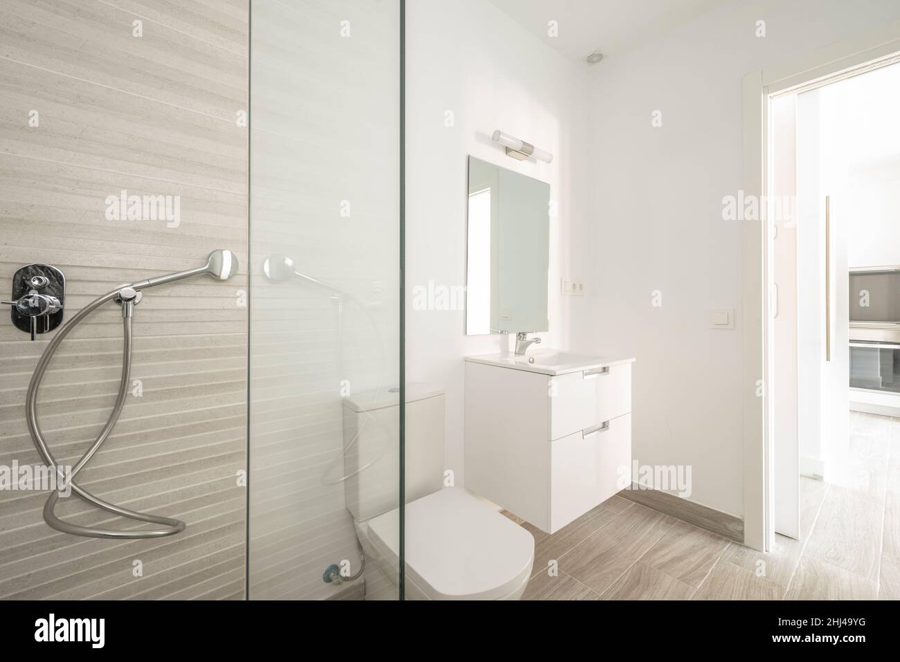 Toilet with shower and white sink, rectangular mirror in shortterm