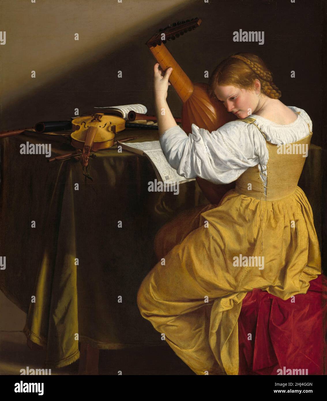 The Lute Player, circa 1612-20 oil painting by Italian Baroque artist Orazio Gentileschi (1563-1639) showing a young woman in a shimmering gold dress intently tuning or playing a lute, seen from three-quarters behind, seated beside a table with songbooks, recorders, a cornetto, and a violin Stock Photo