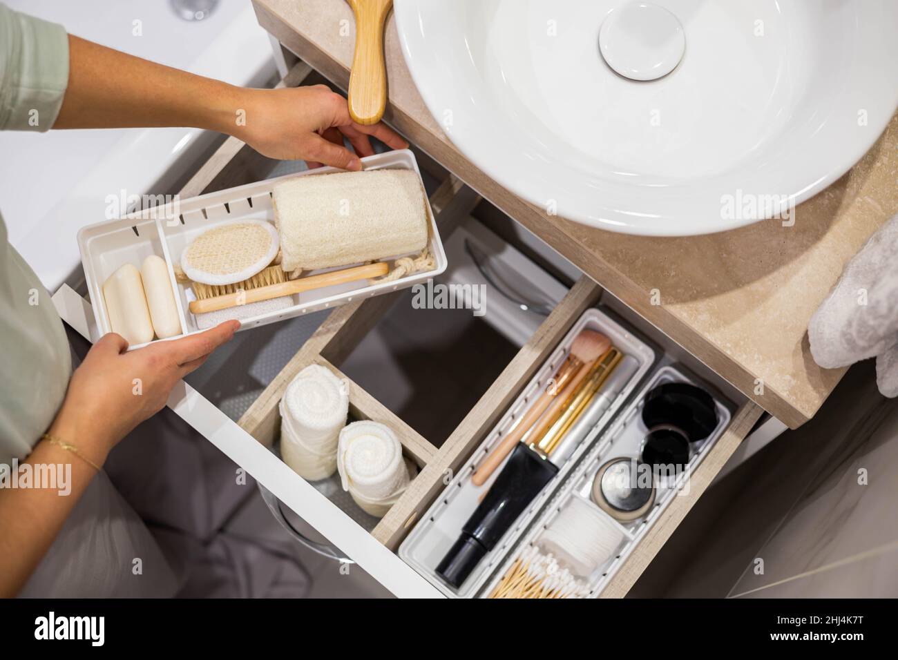Top view of woman hands neatly organizing bathroom amenities and
