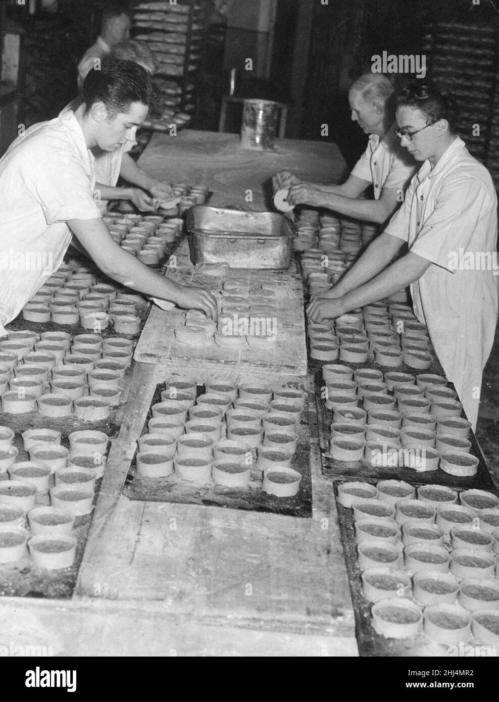 Bakers topping pies about to be put into the oven at a Edinburgh Bakery, Friday 1st February 1957.  Extra supplies are anticipated with large crowds expected  for three matches in the city this Saturday, cafes and restaurants are sure to be busy.   Sottish FA Cup Fifth round matches Hibernian v Aberdeen,  Heart of Midlothian v Rangers and Edinburgh FC v TBC? Stock Photo