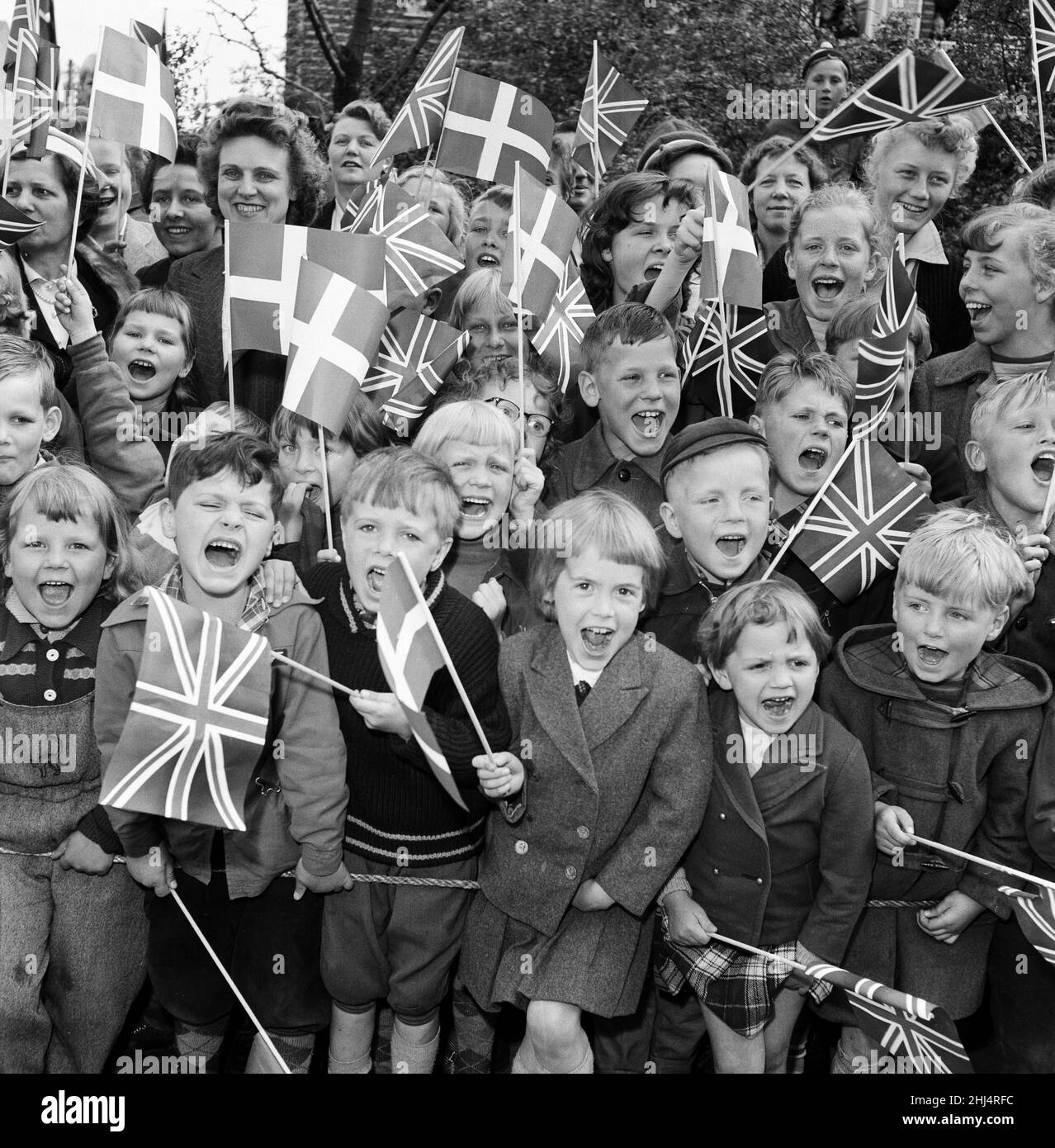 Queen Elizabeth II and Prince Philip, Duke of Edinburgh visit to Denmark. Children with Union Jack flags and Danish flags cheer when Queen Elizabeth II and Prince Philip visit the recreation centre. 22nd May 1957. Stock Photo