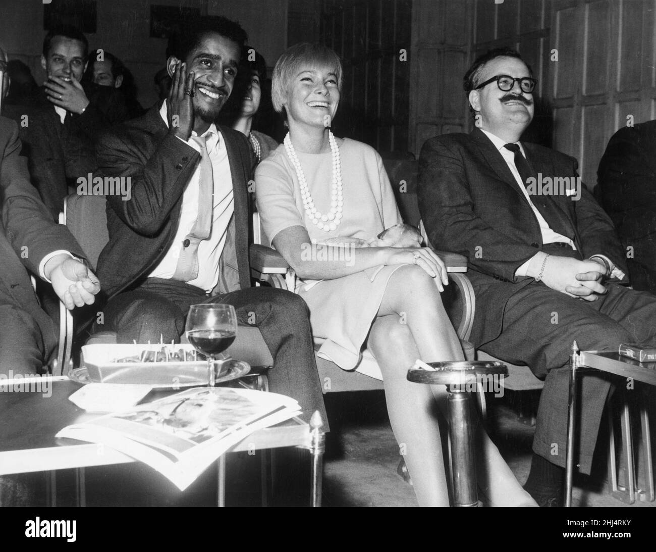 Sammy Davis Jnr with his wife, actress May Britt, watching an extract of his new film 'Sergeants Three' at The Mayfar Hotel, London.3rd October 1961. Stock Photo